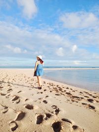 Woman with umbrella on beach against sky