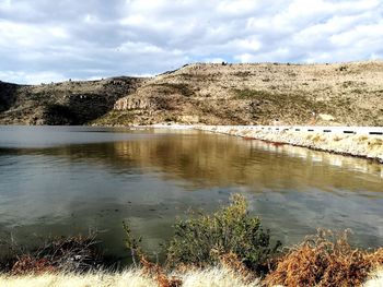 Scenic view of river against cloudy sky