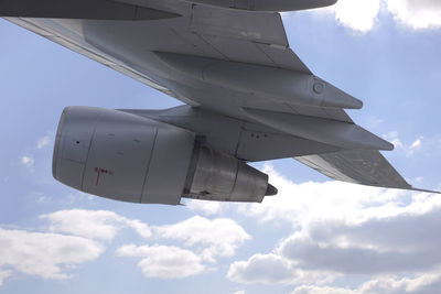 Low angle view of airplane flying against cloudy sky