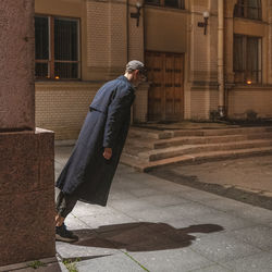 Full length of man leaning forward on street
