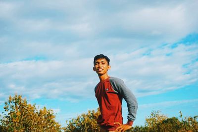 Smiling young man standing against sky