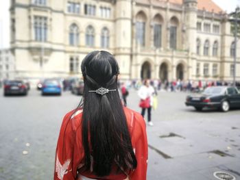 Rear view of woman standing on street in city