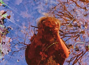 Reflection of woman on tree by lake