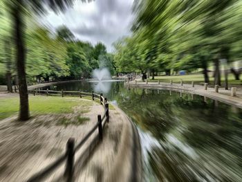 Blurred motion of road amidst trees against sky