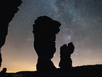 Shadow of man on rock against sky at night