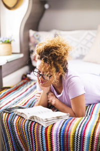 Portrait of smiling young woman sitting on bed at home