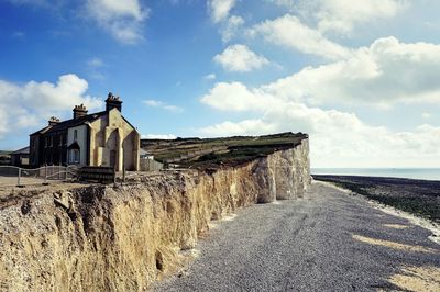 Built structure by sea against cloudy sky