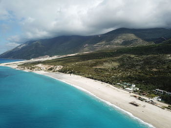 Scenic view of sea by mountains against sky