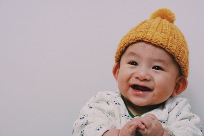 Close-up portrait of cute baby boy looking away against wall