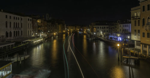 Canal amidst illuminated buildings in city at night