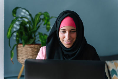 Portrait of smiling mid adult woman sitting on mobile phone