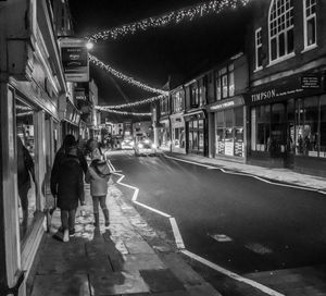 People walking on illuminated street at night