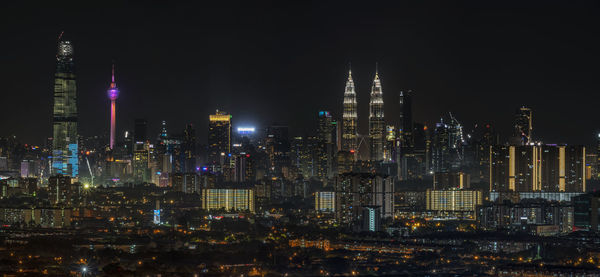 Illuminated buildings in city against sky at night