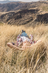 People relaxing on field against mountain