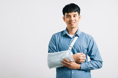 Portrait of young man standing against white background