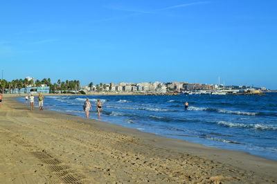 People on beach against blue sky