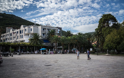 Men walking on street against cloudy sky