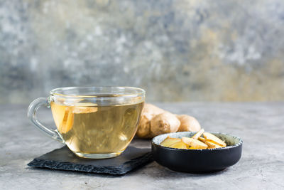 Ginger tea in a cup and chopped root in a bowl on the table. natural vitamins.