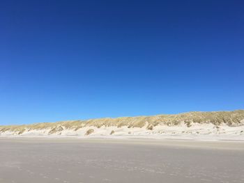 View of empty road against clear blue sky