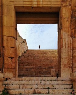 Distant view of woman standing on staircase against sky