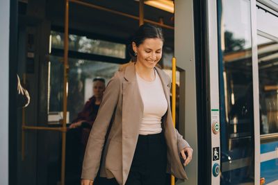 Smiling woman exiting from tram during city exploration