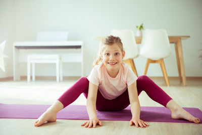 Girl practicing yoga on mat at home