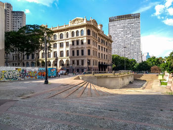 Street by buildings in town against sky