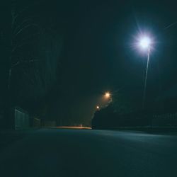 Illuminated road against sky at night