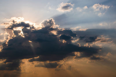 Low angle view of sunlight streaming through clouds