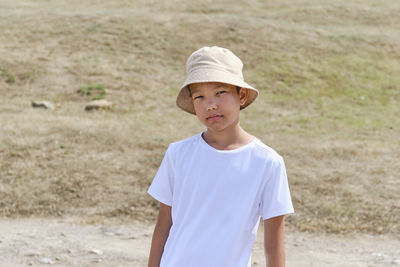 Half-length portrait of an asian boy in white t-shirt and panama hat, against background of nature.