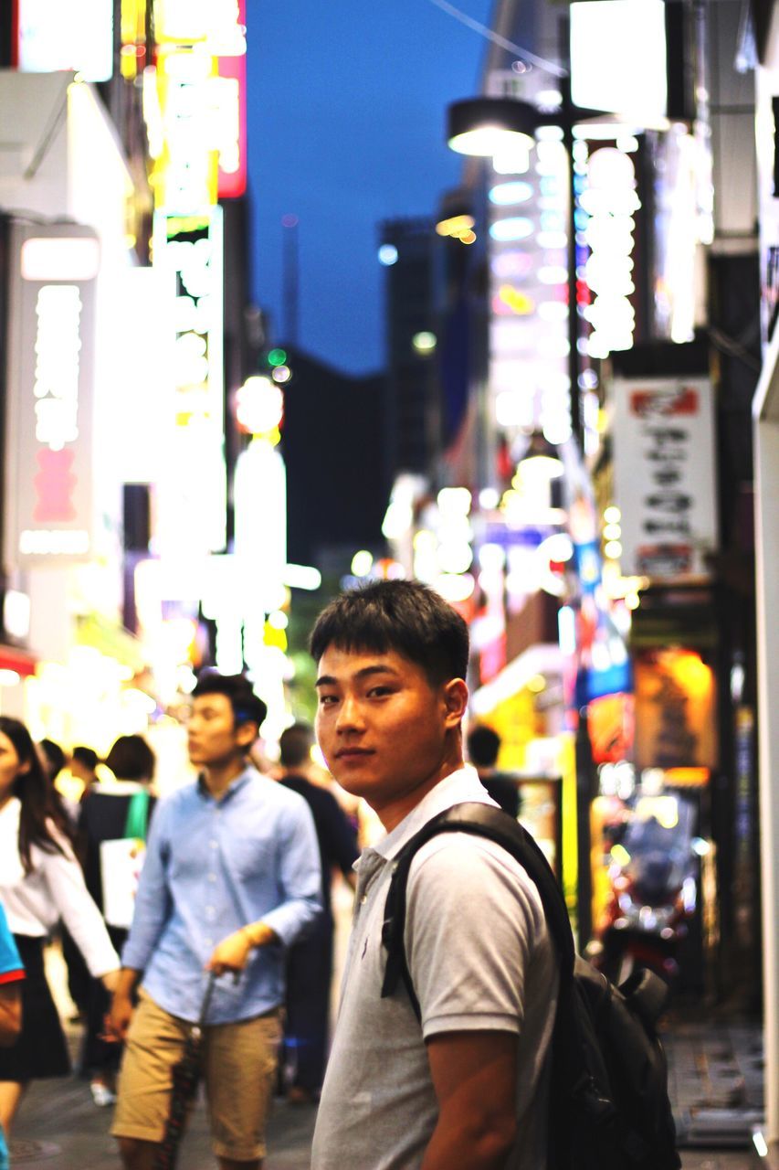 lifestyles, building exterior, focus on foreground, architecture, city, street, built structure, leisure activity, casual clothing, city life, large group of people, incidental people, headshot, person, day, outdoors, standing, waist up