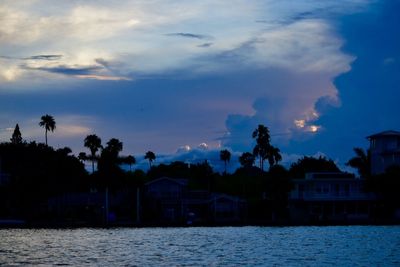 Silhouette houses and trees against sky during sunset