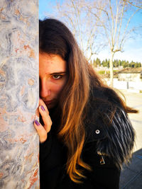 Portrait of beautiful woman hiding by wall