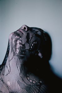 Close-up of teenage girl wearing black fabric by wall