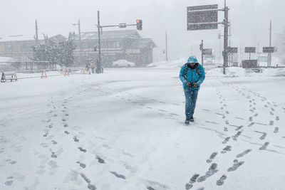 Man walking on snow covered street in city