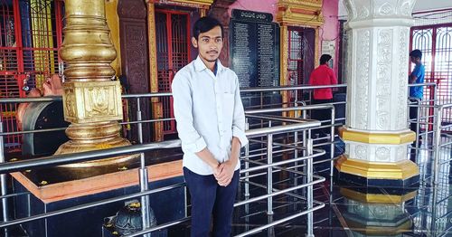 Portrait of young man standing by railing