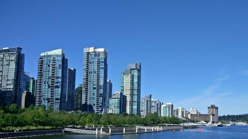 Buildings in city against clear blue sky