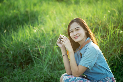 Portrait of a smiling young woman sitting on field