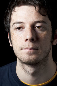 Close-up of young man against black background