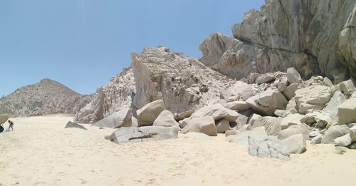 View of rocks on beach against clear sky