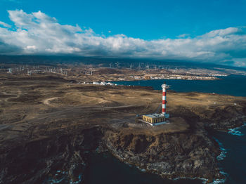 Lighthouse by sea against sky