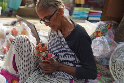 Senior woman in sari making sculpture at market