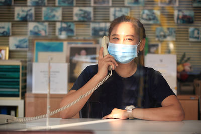 Portrait of businesswoman talking over telephone in office