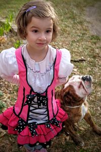 High angle view of thoughtful girl standing by english bulldog sitting on field