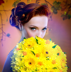 Portrait of bride holding bouquet against orange background