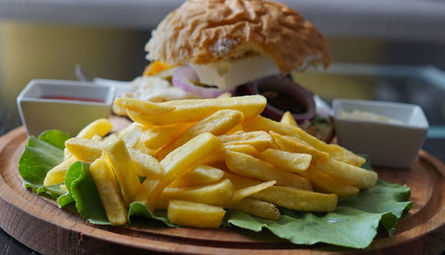 Close-up of french fries with burger on table