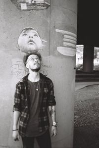 Portrait of young man standing against wall