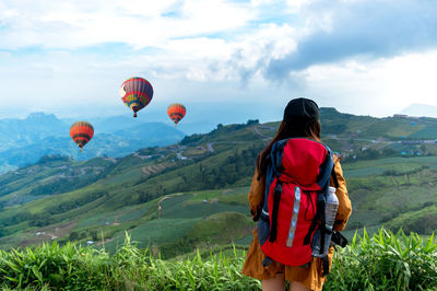 Rear view of man with hot air balloon against sky