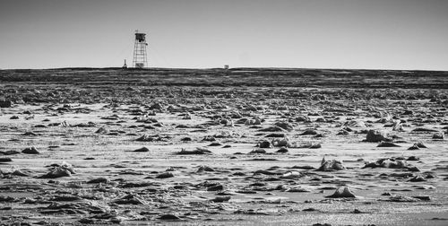Lighthouse on beach against clear sky