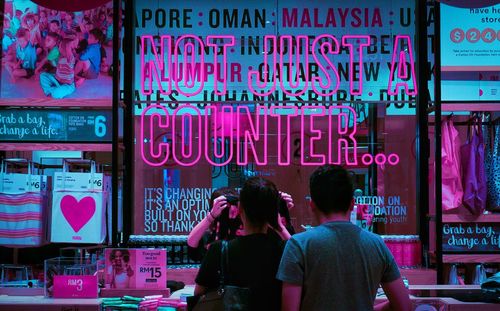 Rear view of people walking in illuminated shop